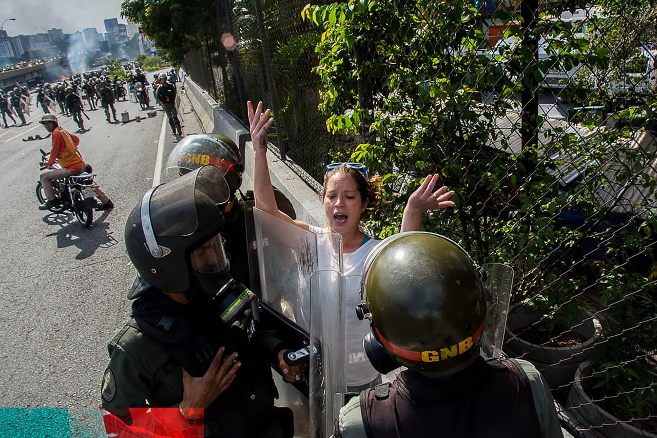 Tres soldados de la Guardia Nacional detienen a una manifestante en Caracas, Venezuela.