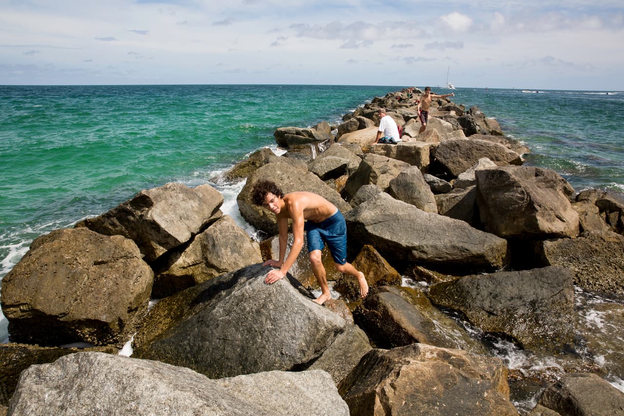 El domingo en la tarde algunas personas atraviesan el rompeolas de piedras para acercarse al lugar donde chocó la lancha de José Fernandez en South Pointe.