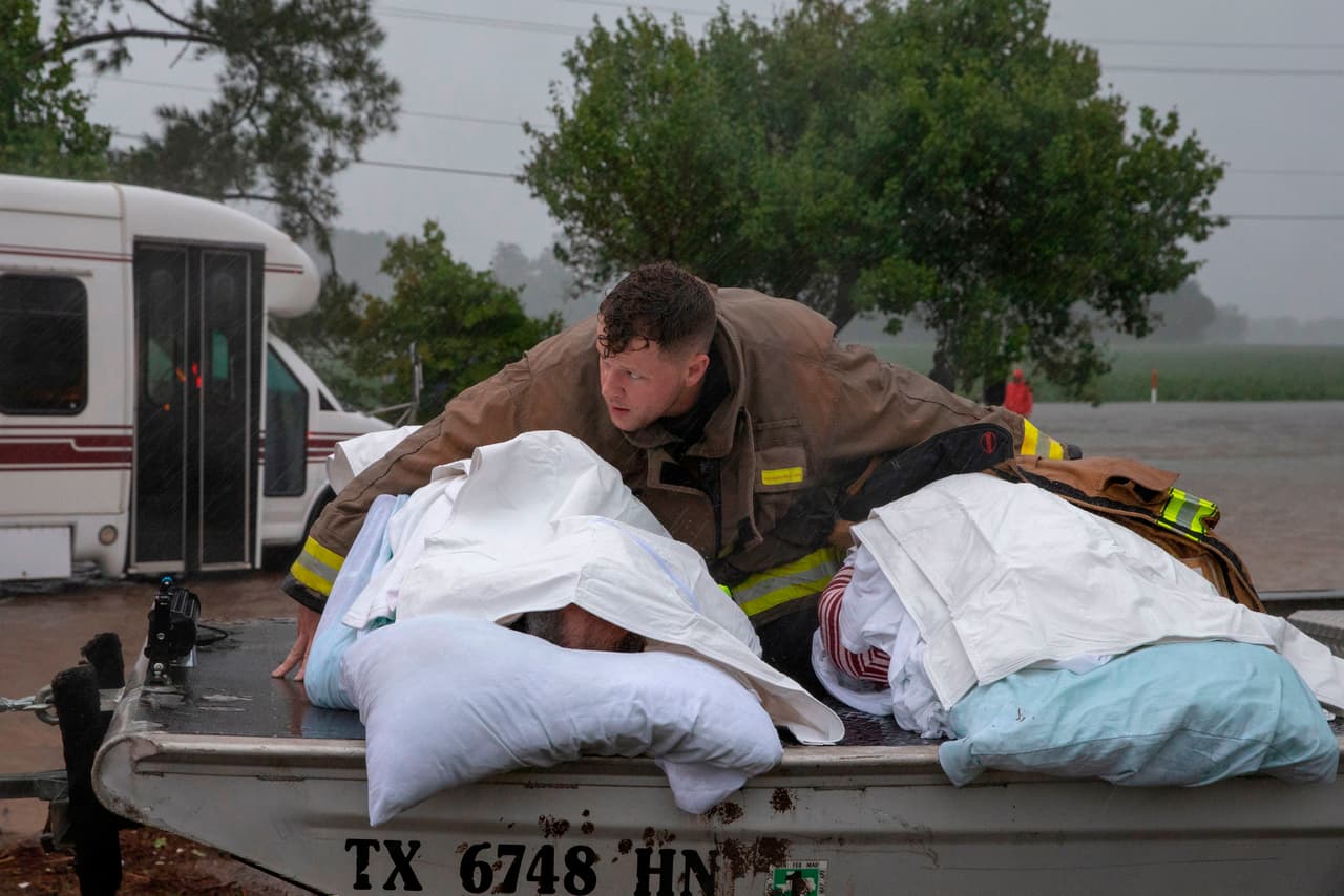 Un bombero protege de la lluvia a dos ancianos evacuados de un asilo en Lumberton, Carolina del Norte. Alrededor de 760,000 clientes de las compañías eléctricas electricidad en Carolina del Norte y 36,000 en Carolina del Sur no tienen electricidad. 
<br>