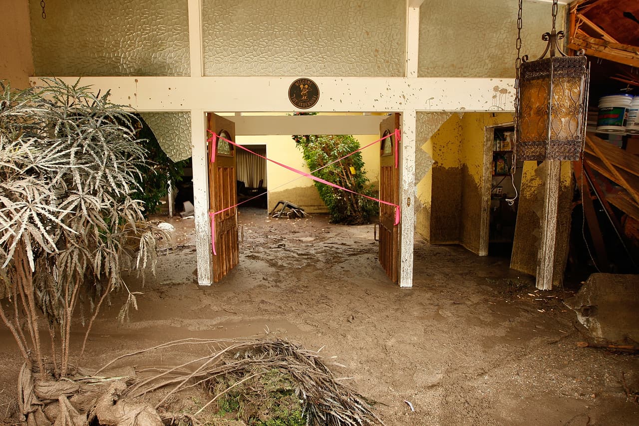 LA CANADA-FLINTRIDGE, CA - FEBRUARY 6: A debris flow damages a home after heavy rains caused mudslides February 6, 2010 in La Canada Flintridge, California. Large wildfires in 2008 and 2009 stripped the hills and mountains of vegetation, resulting in mud and debris flow danger as winter rains pass over foothill communities where thousands of people have been evacuated at times in recent weeks. The threat is particularly high near the San Gabriel Mountains above La Canada-Flintridge area which were denuded of natural flood-controlling vegetation by the 250-plus square mile Station. At least 40 homes have been severely damaged and 500 remain evacuated. (Photo by David McNew/Getty Images)