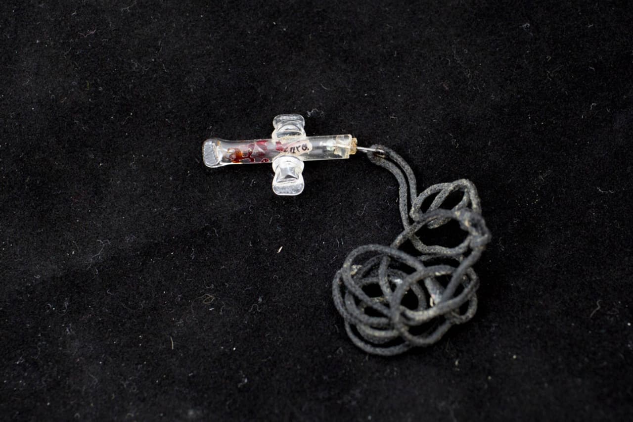 Collar de una cruz con un arroz en donde se leen los nombres “Sara” y “Rigo” que fue encontrado en Mariposa Ranch el 15 de julio de 2012. Se cree que le pertenecía a una mujer de entre 30 y 50 años de edad.