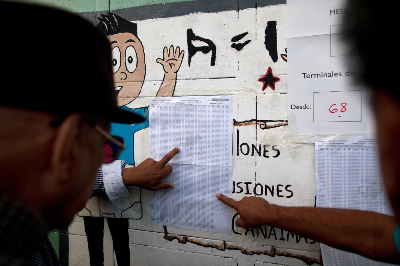 Electores venezolanos buscan su número identificación en un centro electoral.