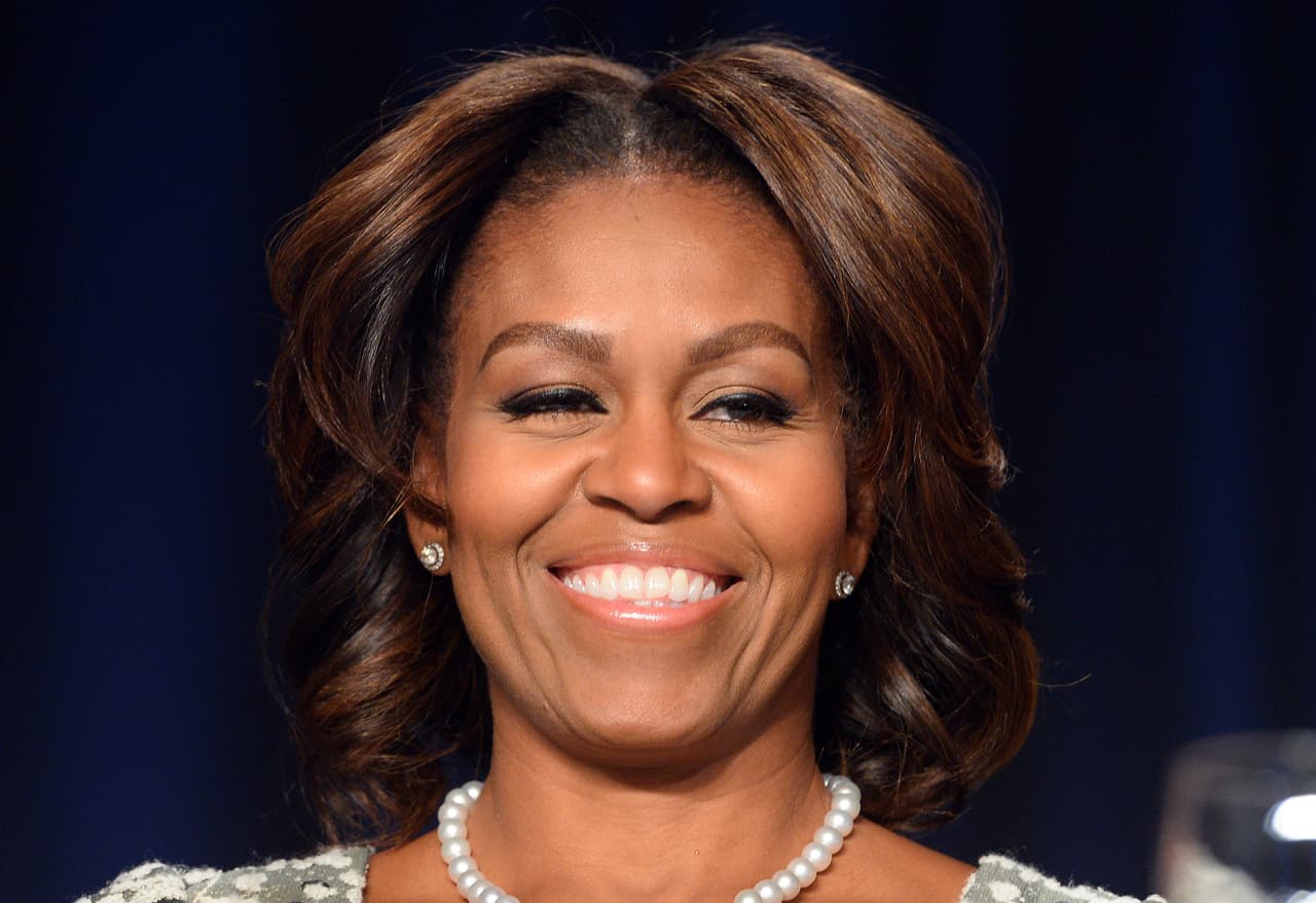Otro cambio dramático en el pelo de Michelle Obama llegó en 2014:
<b> dejó el fleco en el olvido, llevó capas onduladas suaves y una coloración estilo <a href="http://www.refinery29.com/michelle-obama-ombre-hair"><i>ombré</i></a></b> en tonos caoba. Este tipo de reflejos le dieron una notable luminosidad, por lo que se ve más joven que cuando lleva un color plano.
