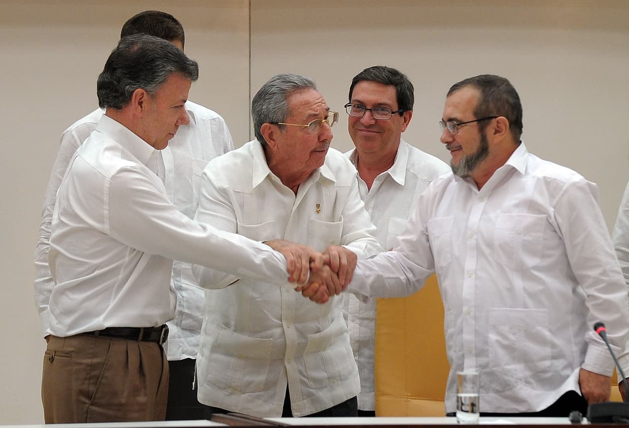 Luego de más de cuatro intensos años de negociación, en agosto de 2016 llegan a un acuerdo que pone fin a 52 años de conflicto. En la foto, Alias Timochenko aprieta la mano a Juan Manuel Santos, durante uno de los encuentros de los diálogos de paz en La Habana, Cuba. En el centro, el presidente de la isla Raúl Castro.