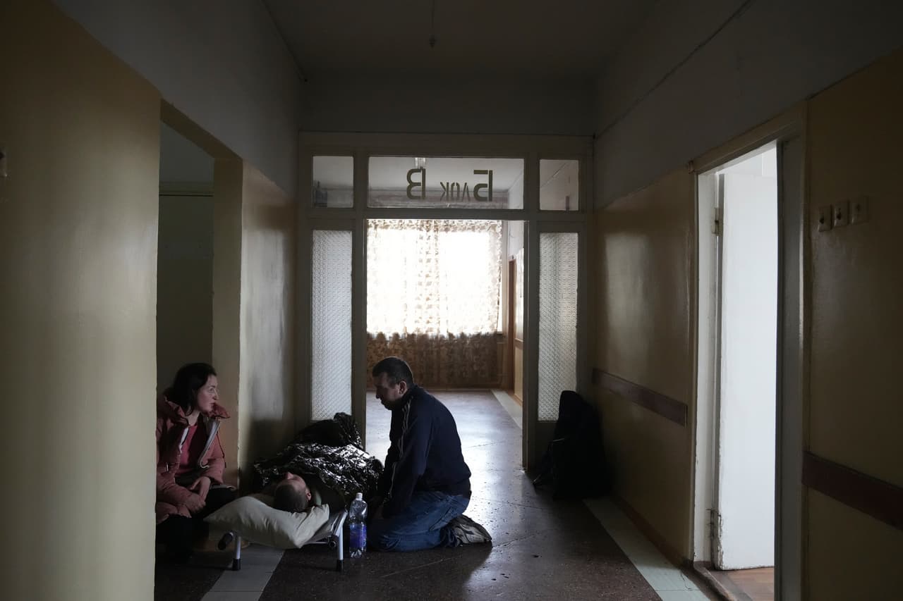 Consuelo a un hombre herido recostado en una camilla. El Ministerio ruso de Defensa dijo que haría un alto el fuego para la "apertura de corredores humanitarios" en 
<b>Mariúpol, pero la evacuación fue frenada porque los bombardeos continuaban, indicó la alcaldía.</b>
<br>