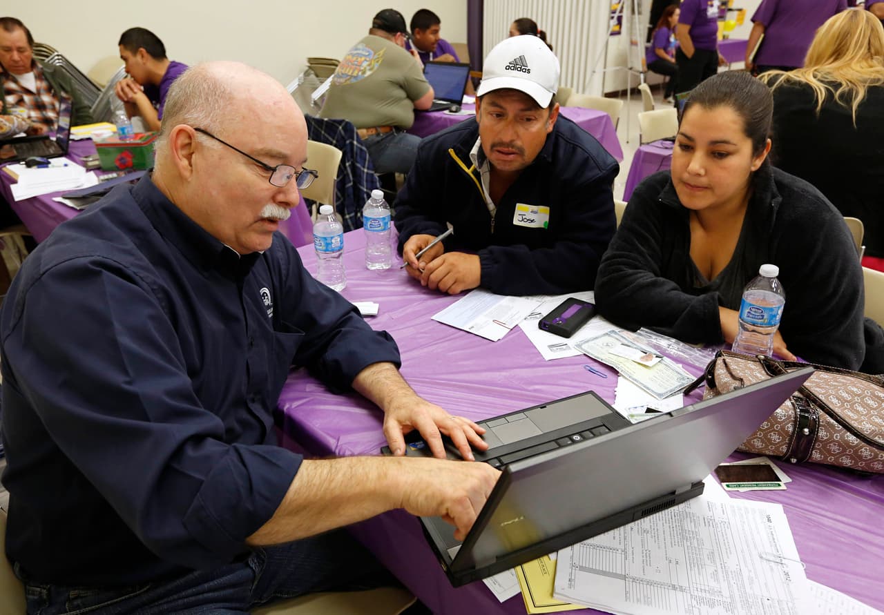 Michael Wilson, left, a certified Cover California insurance agent, explains a health insurance plan to Jose Gomez and his wife, Laura, at a registration site hosted by Service Employees International Union-United Healthcare Workers, Monday, March 31, 2014, in Sacramento, Calif. Dozens attended the event to sign up for health coverage ahead of Monday's midnight enrollment deadline. (AP Photo/Rich Pedroncelli)