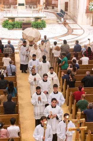 El arzobispo Thomas Wenski lleva el Santísimo Sacramento a través de la iglesia hasta su lugar en la capilla de la Catedral de Saint Mary para la adoración al concluir la misa del Jueves Santo.