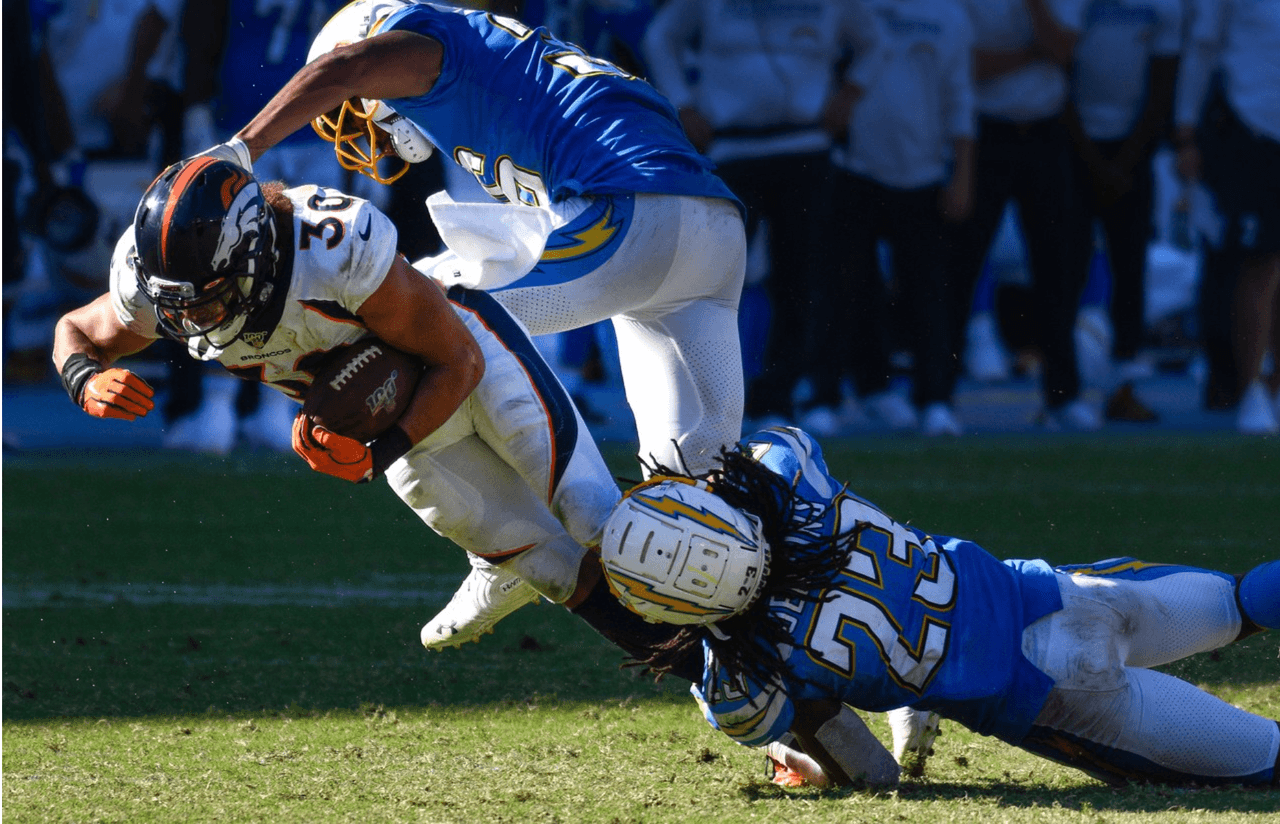 Phillip Lindsay de Denver Broncos trata de avanzar aun contra la tacleade de Roderic Teamer y Rayshawn Jenkins de Los Angeles Chargers.