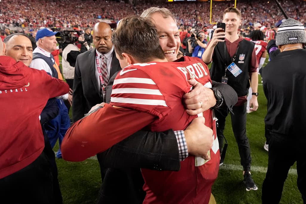 El gerente general de los 49ers de San Francisco, John Lynch, de frente, abraza al mariscal de campo Brock Purdy después del partido de fútbol americano de la NFL por el Campeonato de la NFC contra los Lions de Detroit en Santa Clara, California, el domingo 28 de enero de 2024. (Foto AP/Mark J. Terrill)