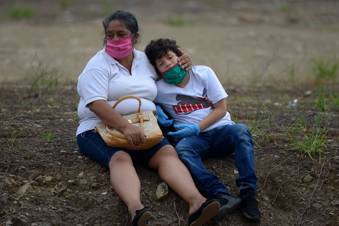 Familiares de un fallecido con máscaras descansan a las afueras de un cementerio de Guayaquil.