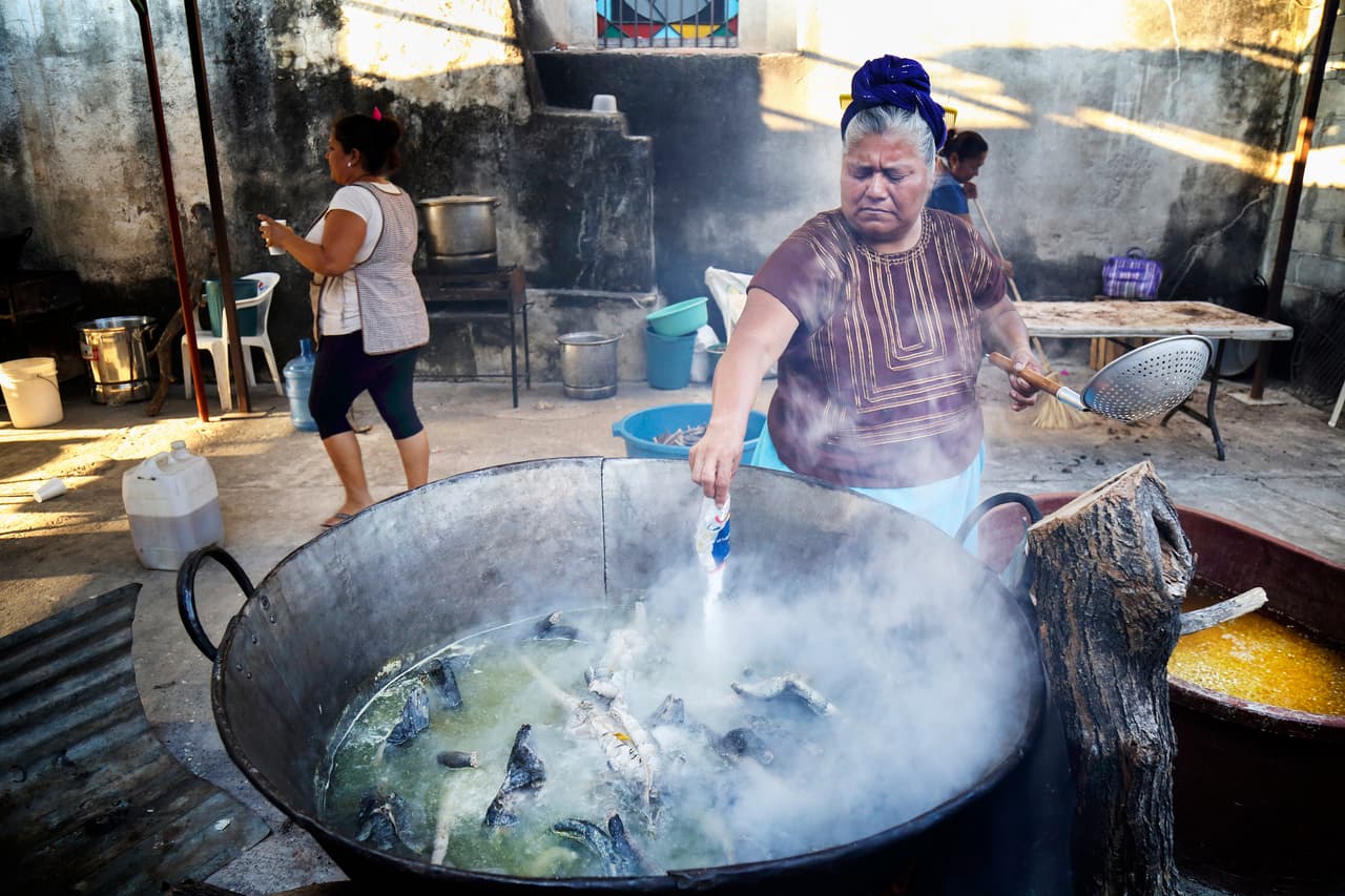 Varias iguanas hervidas en un inmenso caldero, parte de la compleja preparación de su carne.