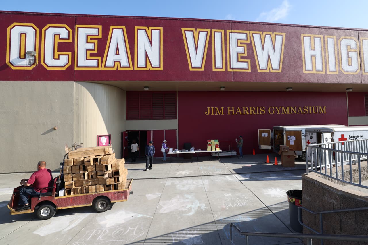 Varias personas llegan a la escuela secundaria Ocean View, un centro de evacuación, después de que un tanque de almacenamiento que contenía un producto químico utilizado para fabricar piezas de plástico se sobrecalentara el jueves en una planta de plásticos aeroespaciales en Garden Grove, el sábado 23 de mayo de 2026 en Huntington Beach, California. (Foto AP/Jill Connelly)