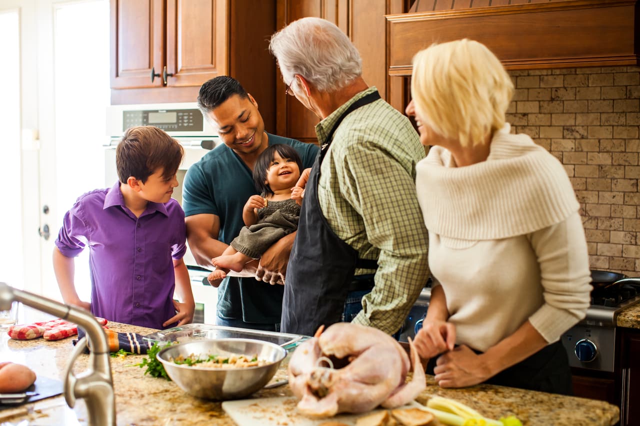 Mixed race family having fun in the kitchen preparing turkey dinner