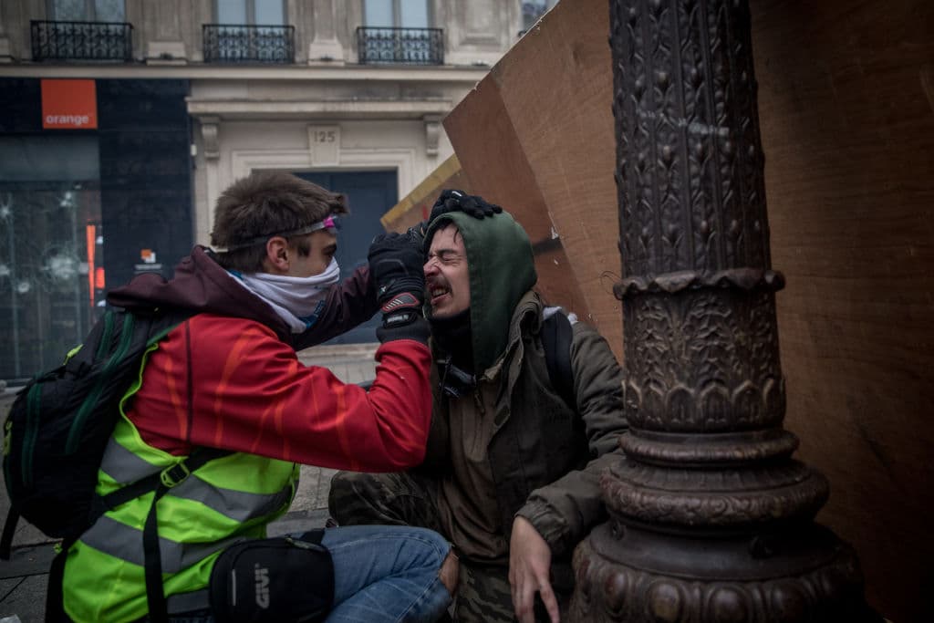 Un manifestante es asistido luego de que la policía disparara gas lacrimógeno durante una marcha de los 'chalecos amarillos' cerca del Arco del Triunfo en París.
