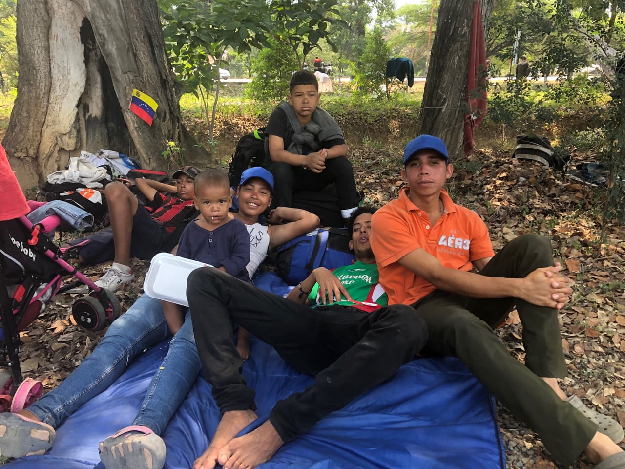 William, de 24 años, (en la imagen con la camiseta verde) llegó al campamento con su esposa, su hijo de un año y medio y unos amigos. “Estamos aquí por un cambio de vida, por conseguir trabajo”, dice. “Allí hay pobreza extrema, mucha maldad. Los más millonarios son ellos y los más pobres nosotros”, añade su amigo Luis (derecha). Dicen que volverán a cuando “caiga el gobierno, cuando esté Guaidó mandando”.