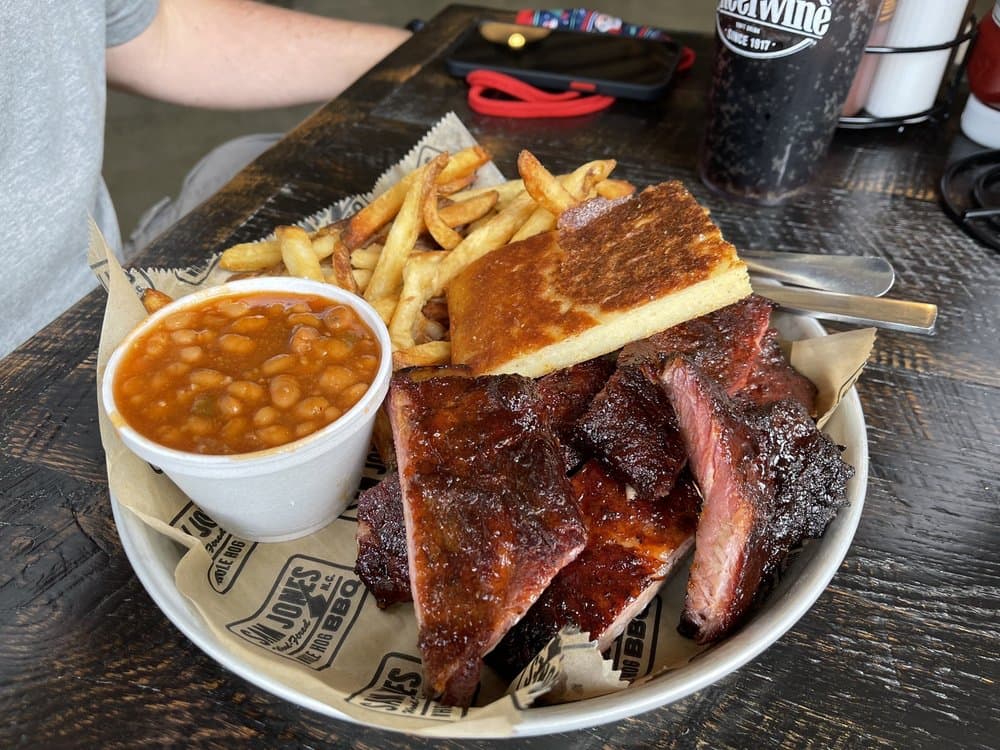 <b>Sam Jones BBQ</b>
<br>Dirección: 502 W Lenoir St. Raleigh, NC. 27601
<br>Teléfono: (984) 206-2555
<br>Sitio web: 
<a href="http://www.samjonesbbq.com">www.samjonesbbq.com</a> 
<br>
<b><a href="https://www.yelp.com/map/sam-jones-bbq-raleigh">Cómo llegar</a></b>
<br>
<br>Una usuaria de Yelp dijo: “Increíble barbacoa de Carolina del Norte. Ven aquí para disfrutar de algo real. Probamos tantos platillos como pudimos y nos llevamos un poco de budín de plátano a casa. Prepárate para irte sintiéndote lleno hasta el tope”.