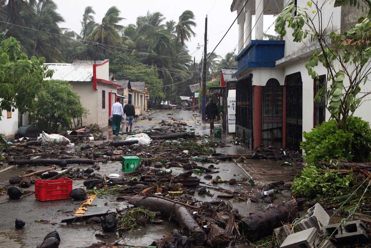 Tres personas caminan por una calle cubierta de escombros en la ciudad de Nagua, mientras el huracán Irma se aleja de la costa norte de República Dominicana luego de que más de 5,500 personas fueron evacuadas en el país.