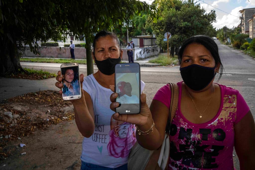 Two mothers show the photos of their sons who were arrested during the July 11 protests, in front of the court building where they are being tried in Havana, Cuba, Tuesday, Jan. 11, 2022.