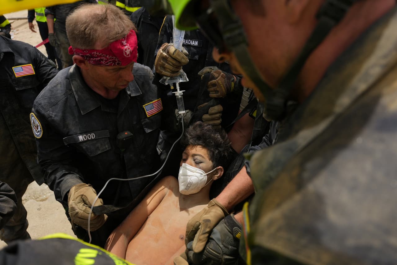 Bomberos estadounidenses del equipo de búsqueda y rescate del condado de Fairfax sacan a un niño de entre los escombros tras rescatarlo a él y a su padre de un edificio que se derrumbó durante los terremotos en La Guaira, Venezuela, el domingo 28 de junio de 2026. (Foto AP/Matias Delacroix)