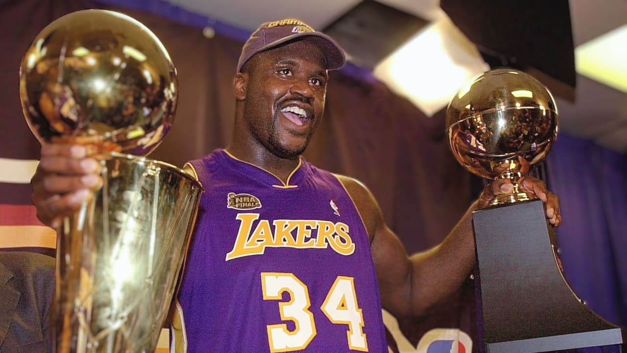 Shaquille O'Neal sostiene el trofeo MVP y el trofeo Larry O'Brian Championship después de que Los Angeles Lakers ganaran el quinto partido de las Finales de la NBA contra los Philadelphia 76ers el 15 de junio de 2001 en el First Union Center de Filadelfia, Pensilvania.