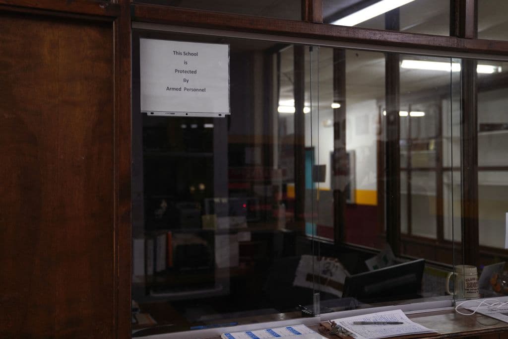 El cartel en la escuela de Utopia que advierte sobre personal armado dentro de la institución.