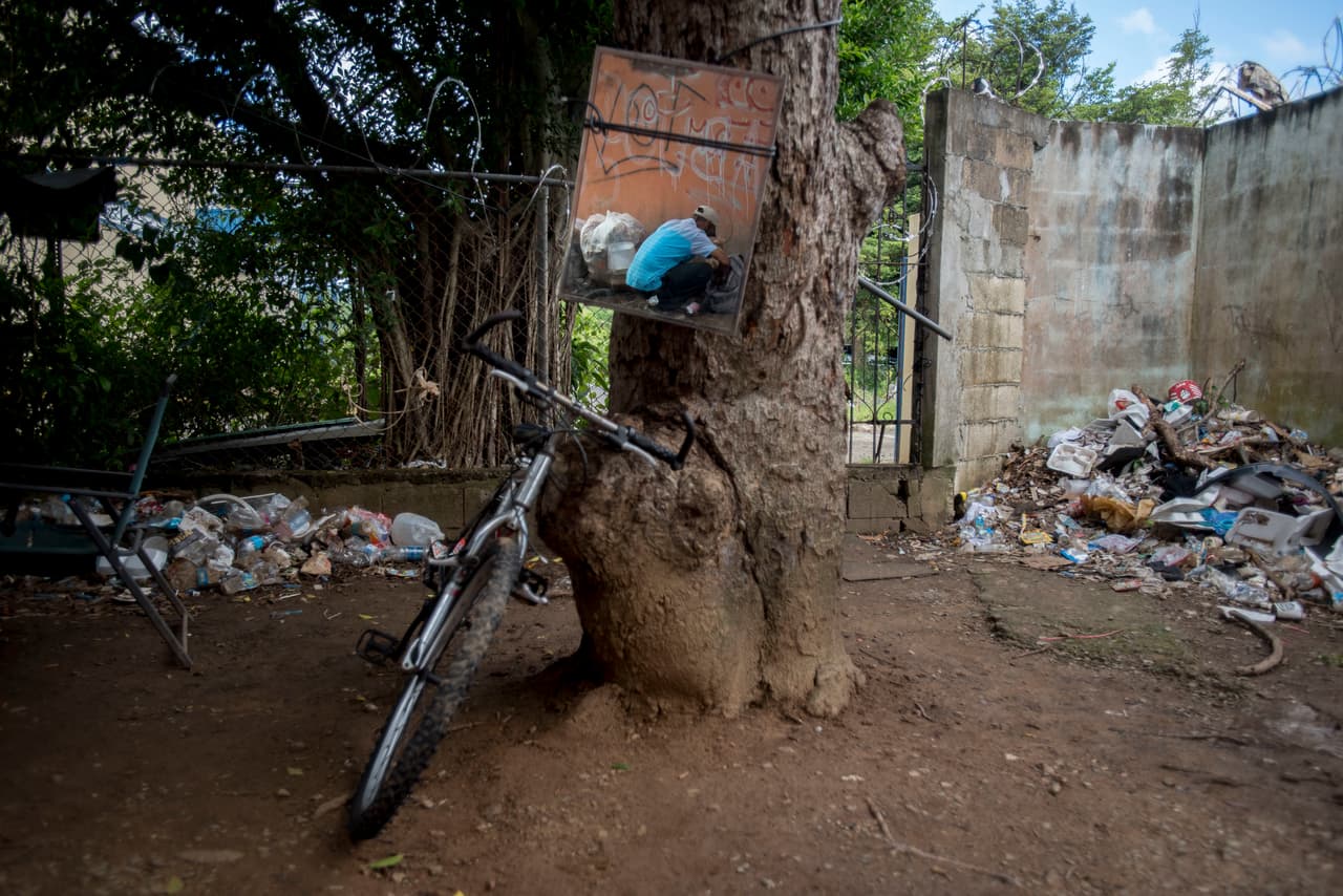 Un espejo atado a un árbol refleja a un adicto preparándose para inyectarse heroína en una casa abandonada de Humacao. A los adictos les gusta verse en espejos cuando se inyectan, sobre todo cuando lo hacen en el cuello.
