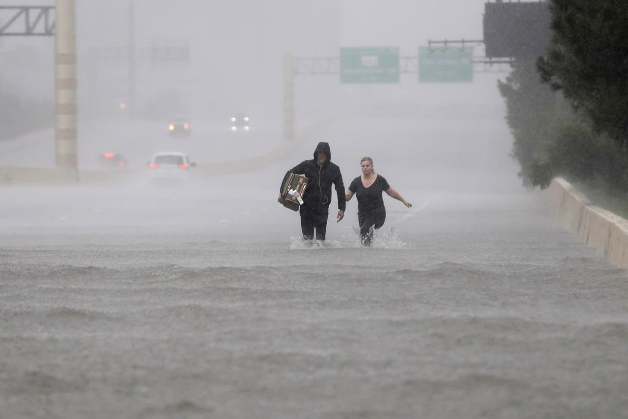 Dos personas caminan por una sección inundada de la Interstatal 610.