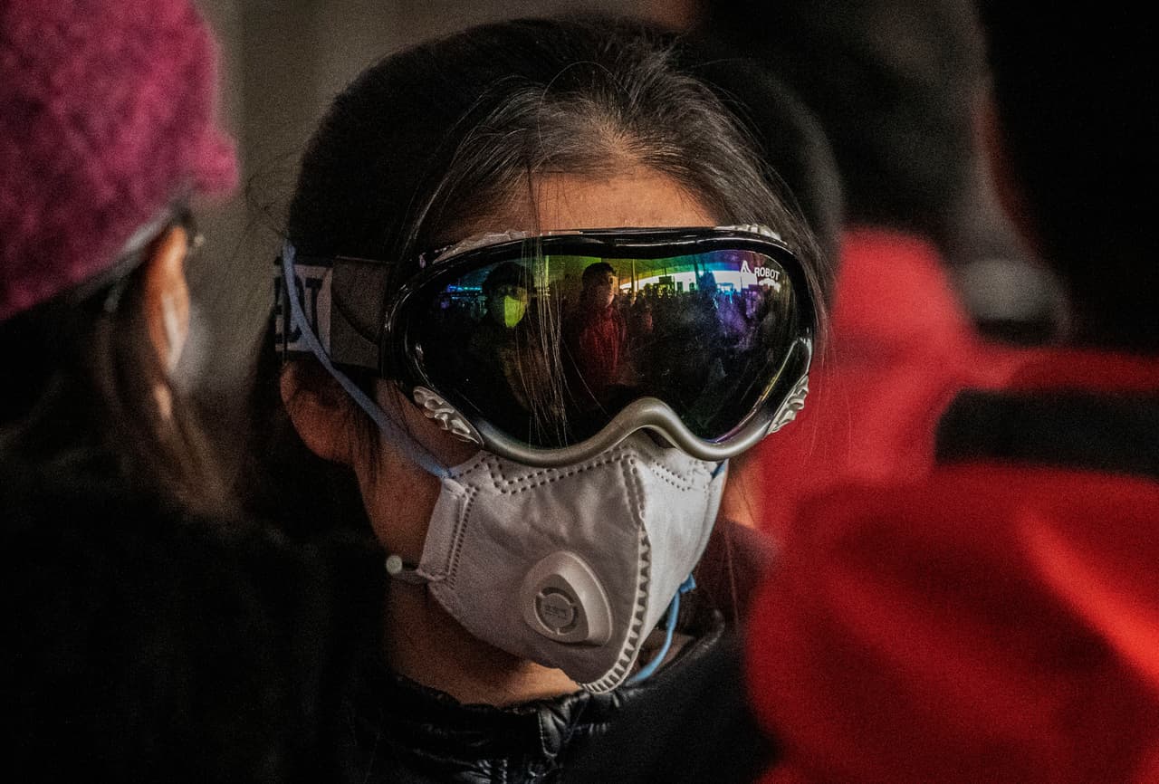 Lentes para esquiar sobre la máscara facial, la protección de una mujer en un aeropuerto de Beijing. 30 de enero.