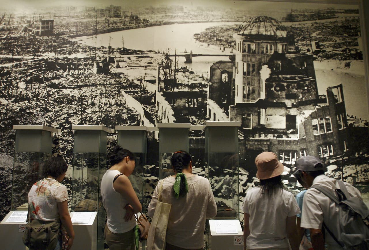 Visitantes del Parque Conmemorativo de la Paz de Hiroshima miran una fotografía tomada en 1945 del área que rodea el 'Domo de la Bomba Atómica', el 5 de agosto de 2004.