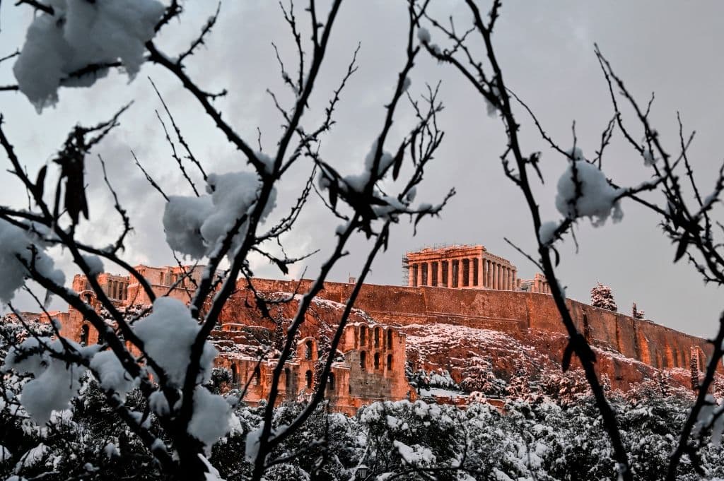 El sol poniente ilumina la Acrópolis tras la intensa nevada. Las autoridades recomendaron la reducción de los desplazamientos y anunciaron la anulación el martes del programa de vacunación contra el covid-19 en Ática, región de Atenas.