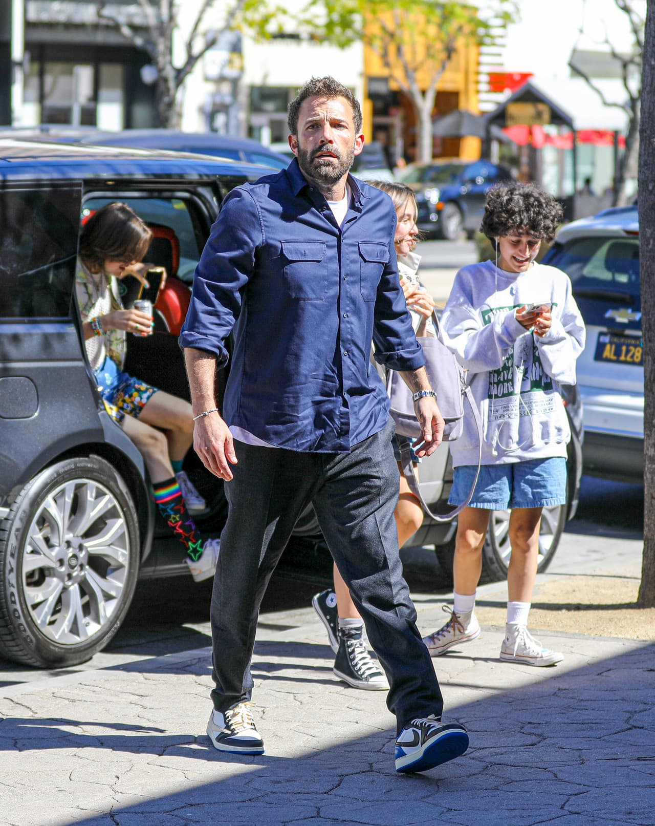 Optó por pantalones cortos largos con estampado azul, un top de punto color crema y una camisa tropical 'oversize'. 
<br>