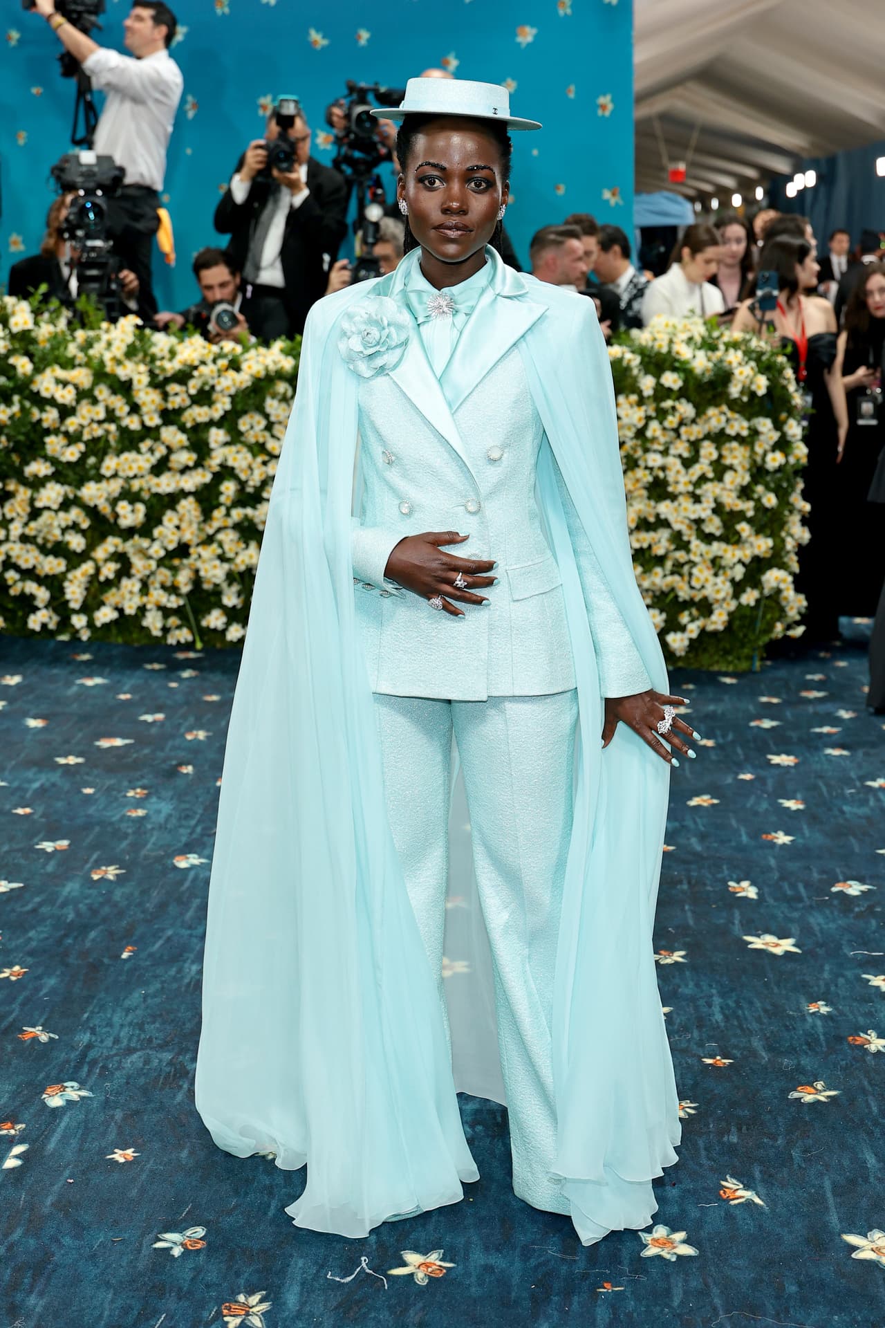 Lupita Nyong’o apareció usando un traje azul claro de Chanel, que combinó con un sombrero y una capa transparente a juego.