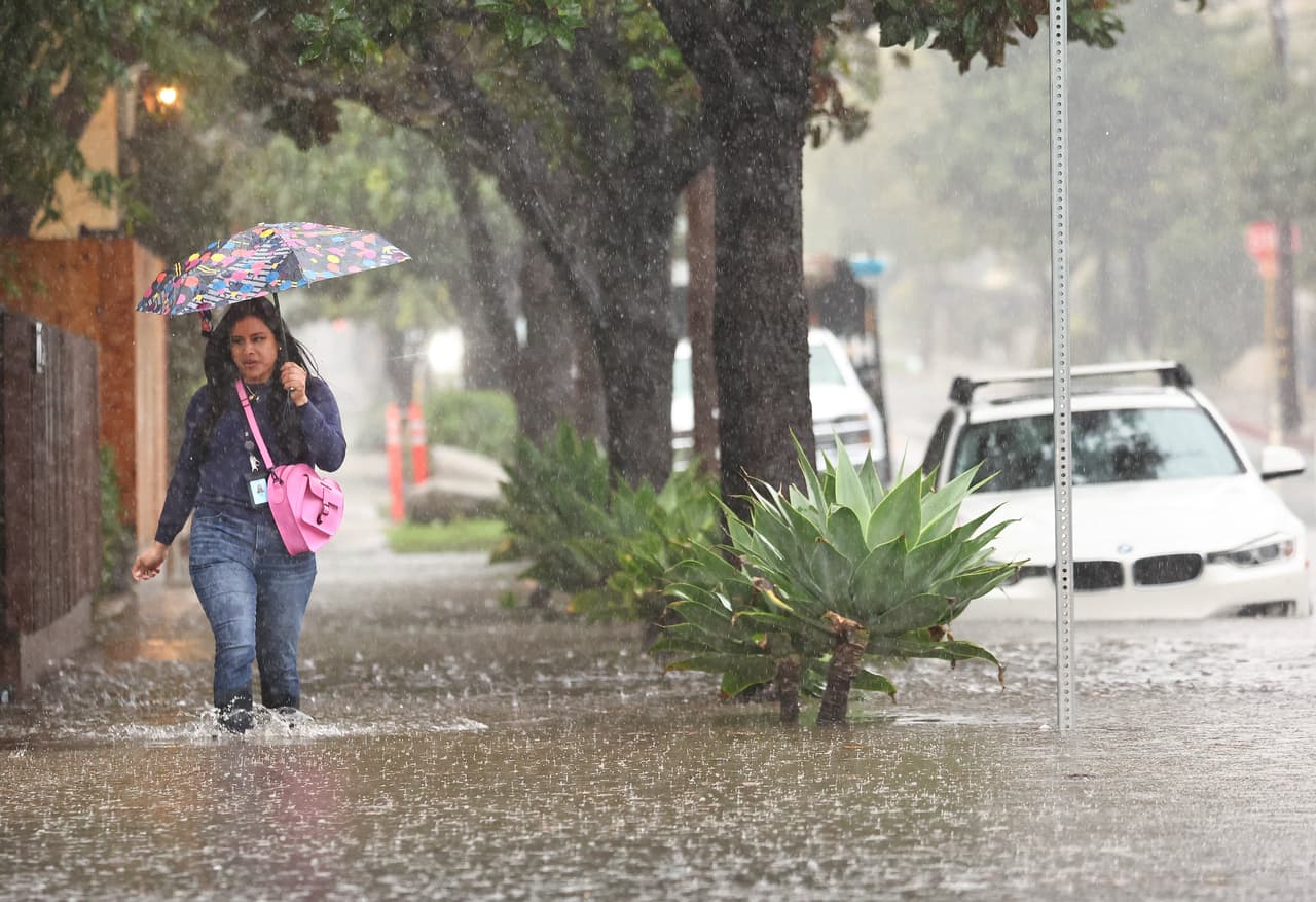 Una persona camina a través de una calle inundada tras el paso de una poderosa tormenta de río atmosférico de larga duración, la segunda en menos de una semana que afecta al norte y sur California.