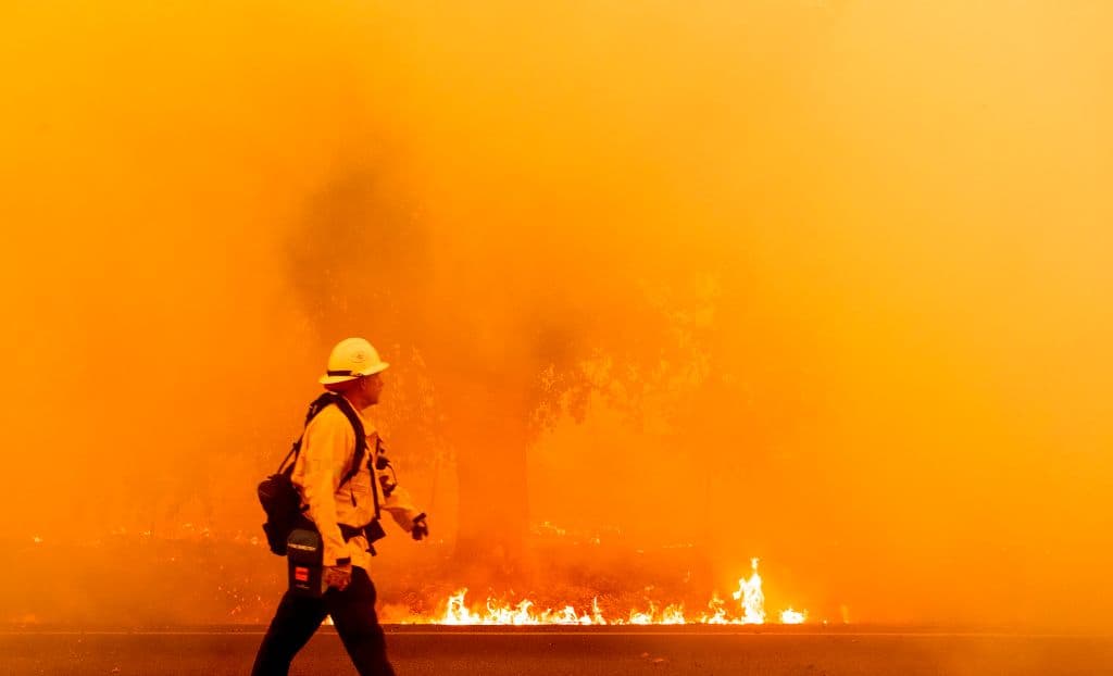 Un bombero de Pacific Gas and Electric camina por una carretera mientras las llamas se acercan en Fairfield, California durante el incendio del LNU Lightning Complex el 19 de agosto de 2020.