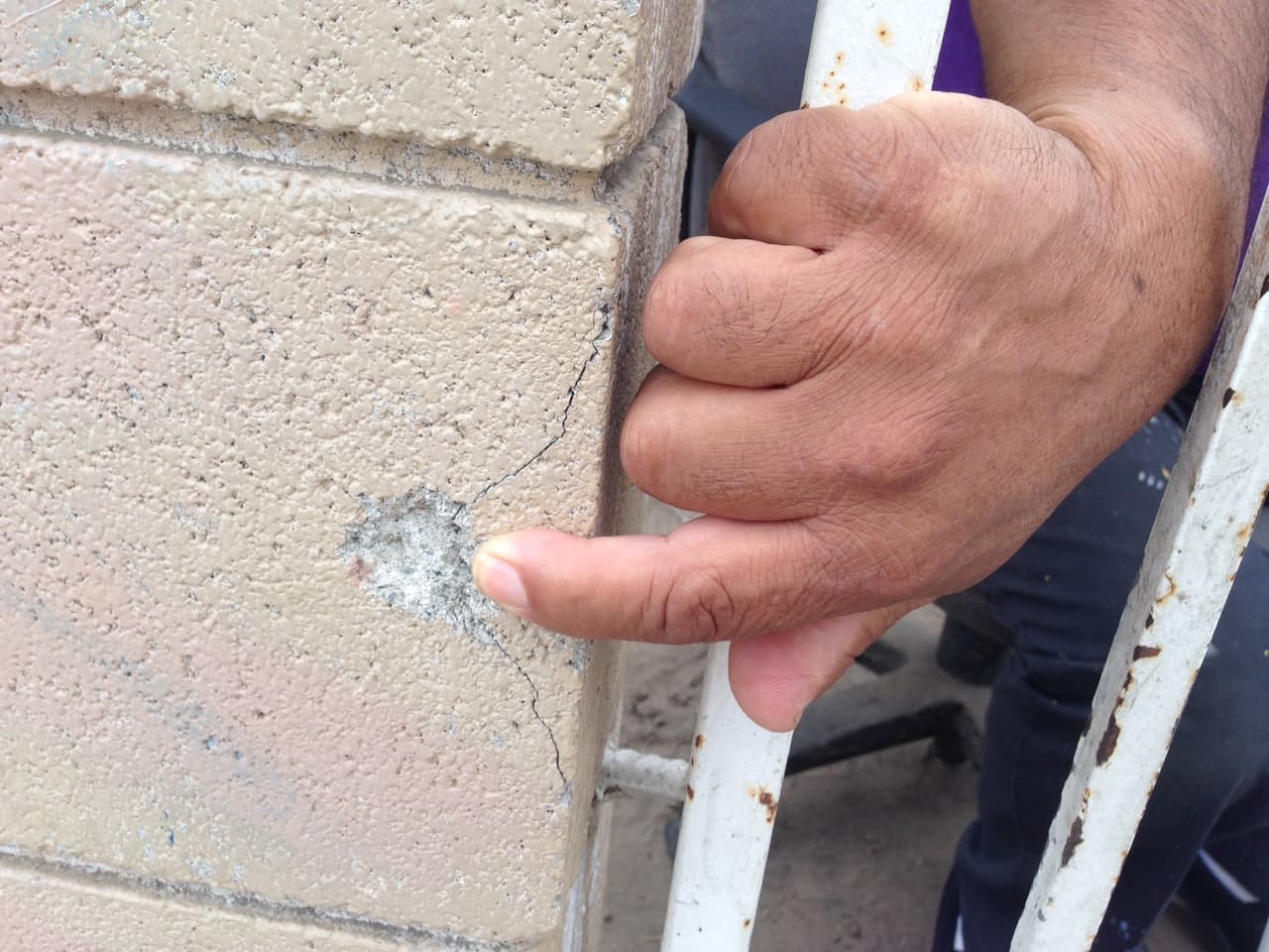 Un vecino de Compton, California, señala la perforación de una bala en la barda de su vivienda.