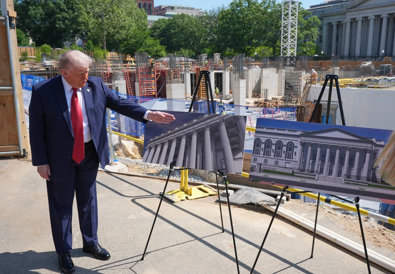 Donald Trump observa los planos del proyecto durante una visita a las obras del nuevo salón de baile de la Casa Blanca. A sus espaldas se aprecia la estructura de la construcción, mientras las imágenes muestran el diseño que tendrá el edificio una vez terminado.