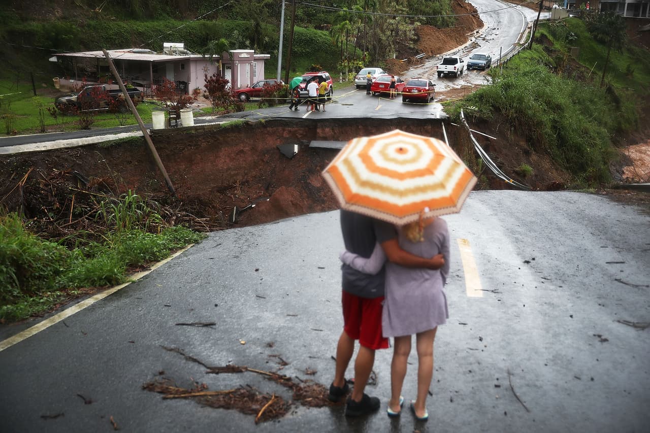BARRANQUITAS, PUERTO RICO - OCTOBER 07: People look on at a section of a road that collapsed and continues to erode days after Hurricane Maria swept through the island on October 7, 2017 in Barranquitas, Puerto Rico. Puerto Rico experienced widespread damage including most of the electrical, gas and water grid as well as agriculture after Hurricane Maria, a category 4 hurricane, passed through. (Photo by Joe Raedle/Getty Images)