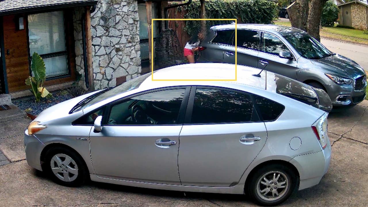 En un video de seguridad, se observa cómo una adolescente se esconde detrás de un auto después de ser aparentemente perseguida por otro vehículo.