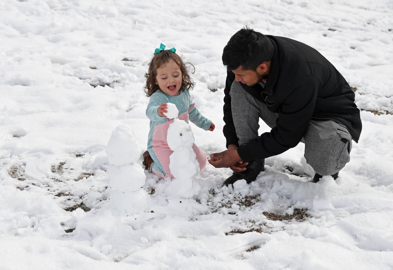 Elmer Cruz de Nevada y su hija de 2 años Alison Cruz construyen muñecos de nieve después de la tormenta de invierno