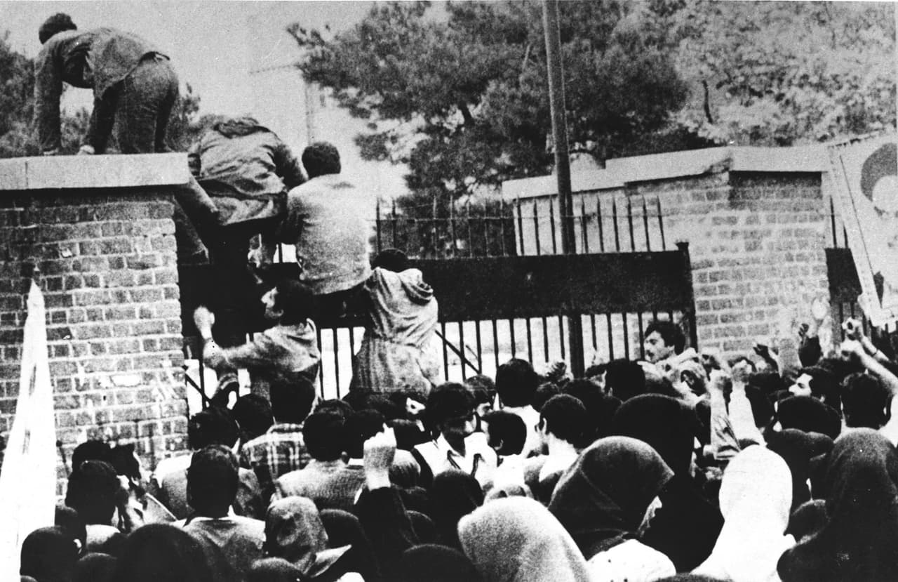 El momento en que estudiantes iraníes trepan un muro de la embajada de EEUU en Teherán el 4 de noviembre de 1979.