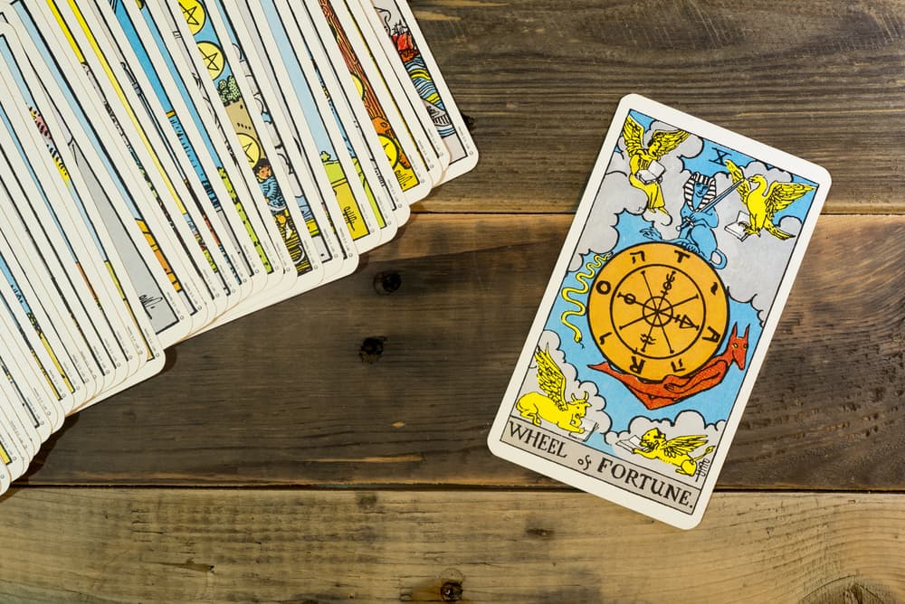 La Rueda de la Fortuna es la décima carta dentro de los Arcanos Mayores (las 22 cartas esenciales del tarot) y curiosamente es una de las que no tiene una figura humana como el punto de enfoque central. En cambio, tiene varias figuras y símbolos relacionados con el Zodiaco y se ve en las nubes porque simboliza el plano superior, celestial, donde se tejen nuestros destinos.