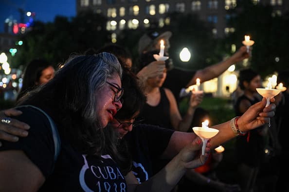 Una mujer llora, abrazada por otra persona doliente mientras guardan silencio y rinden homenaje a las víctimas de las trágicas inundaciones en Texas en Travis Park, San Antonio, la noche del lunes.