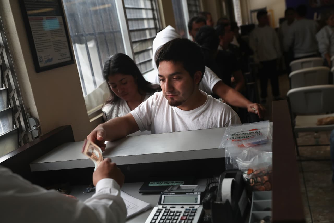 Un guatemalteco cambia sus dólares por quetzalez, la moneda local de Guatemala. Fue deportado desde Texas el 9 de febrero de 2017. En 2016 Estados Unidos deportó a Guatemala a 35,465 personas, un 13% más respecto a los 31,443 deportados en 2015. A pesar de ello, según cifras del Banco de Guatemala, las remesas enviadas por los inmigrantes a sus familiares desde Estados Unidos sumaron 7,700 millones de dólares.