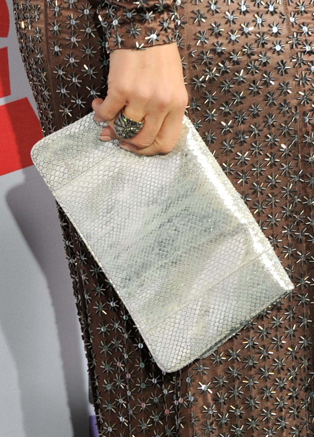 Un vestido café con detalles plateados combinó perfecto con un bolso plateado.