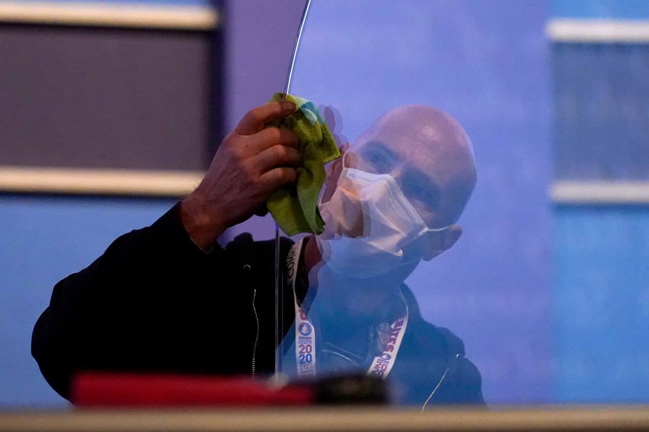 Un miembro del equipo de producción limpia la barrera transparente que servirá para evitar la propagación del covid-19, durante los preparativos para el primer y único debate vicepresidencial en la Universidad de Utah. 
<br>