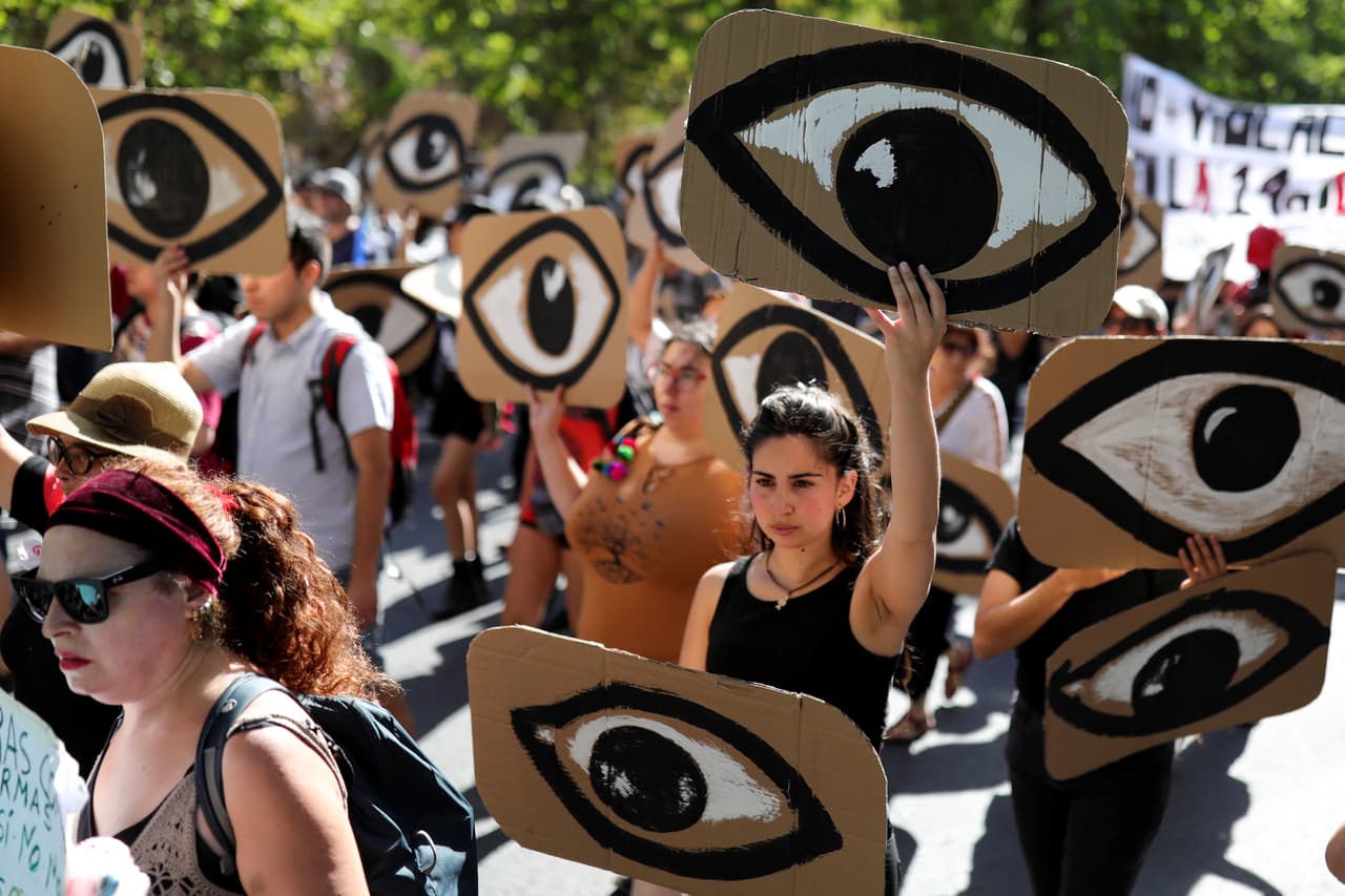 Una joven manifestante levanta una pancarta con un ojo para protestar en contra del gobierno chileno el 10 de diciembre del 2019. 
<b><a href="https://www.hrw.org/es/news/2019/11/26/chile-llamado-urgente-una-reforma-policial-tras-las-protestas" target="_blank">De acuerdo con Human Rights Watch</a></b>, "el Instituto Nacional de Derechos Humanos (INDH) presentó ante el Ministerio Público 442 querellas en representación de víctimas de presuntas lesiones –especialmente lesiones oculares–, tratos crueles, torturas, abusos sexuales, homicidios y tentativas de homicidios atribuibles a fuerzas de seguridad".
