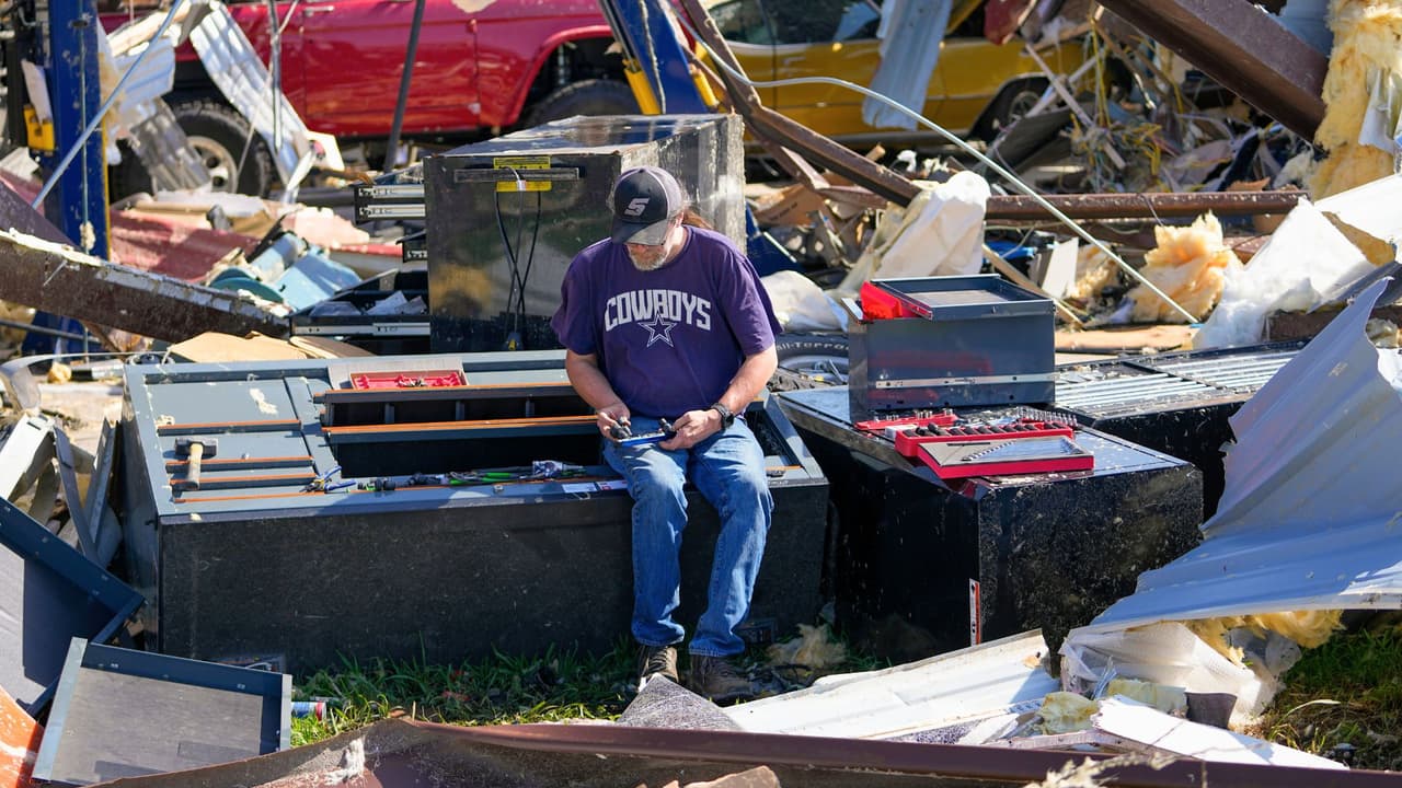Un empleado de un taller recoge herramientas de cerca de los daños la mañana después de que un tornado pasara, el domingo 26 de mayo de 2024, en Valley View, Texas.