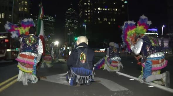 Bailarines se arrodillan durante la fiesta guadalupana en el centro de Dallas.