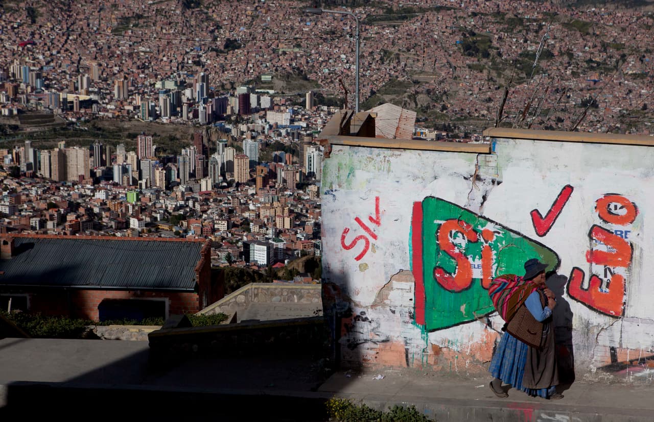 Una mujer aymara camina junto a una pinta sobre el referendo