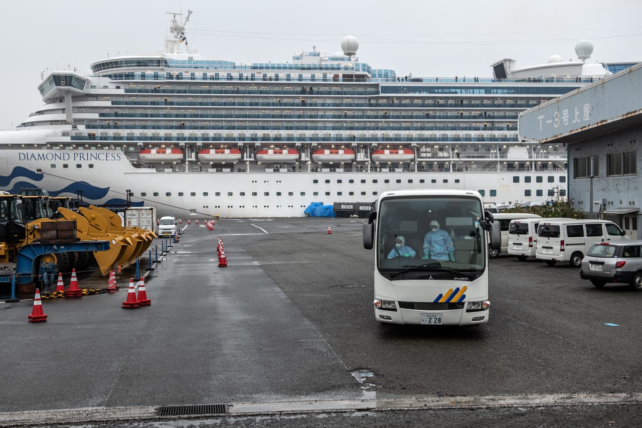 Un conductor maneja un autobús con ropa de protección completa al salir de la zona de estacioamiento del crucero en cuarentena Diamond Princess en Daikoku Pier el 16 de febrero de 2020 en Yokohama, Japón.